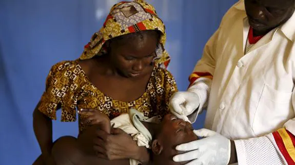 Un niño nigeriano junto a su madre, atendido por un médico.