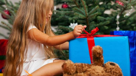 Niña desenvuelve uno de sus regalos el día de Reyes. 