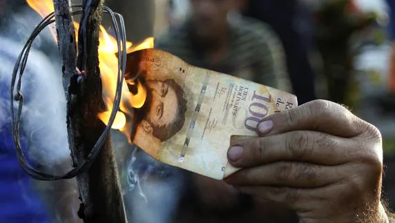 Un venezolano quema un billete. 