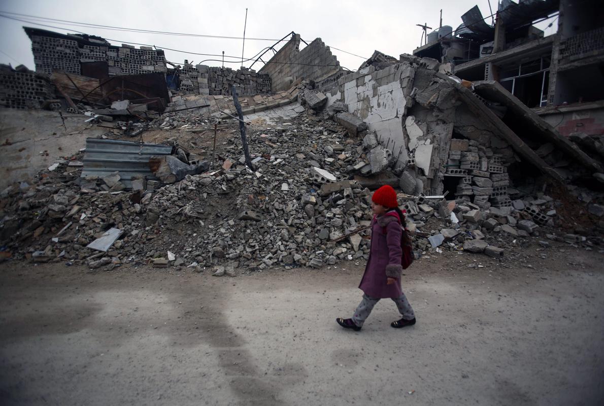 Una niña siria camina junto a casas destruidas en Douma, a las afueras de Damasco. 