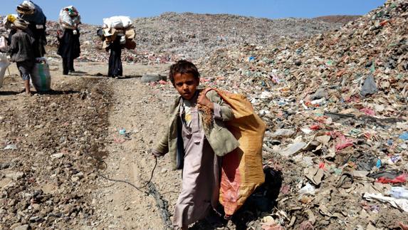 Un niño yemení recoge carga con una bolsa en un basurero. 