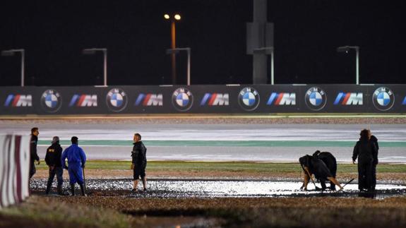 Trabajadores tratan de poner a punto el encharcado circuito de Losail. 