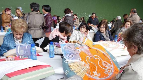 Una mujer trenza los bolillos en un encuentro de encajeras.