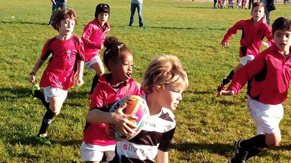 Niños divirtiéndose practicando rugbi.
