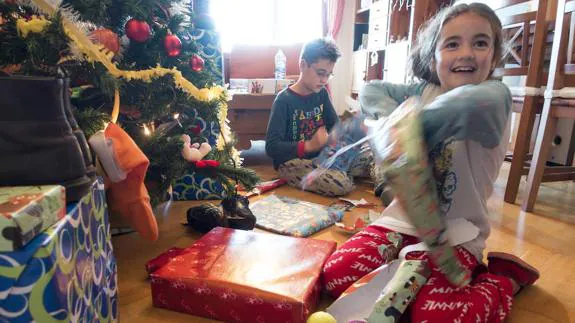 Dos niños abren los regalos en la mañana de Reyes. 