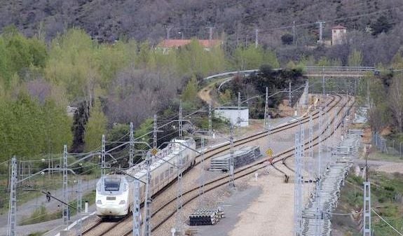 Un Alvia circula por La Robla, al lado de traviesas destinadas a la Variante.