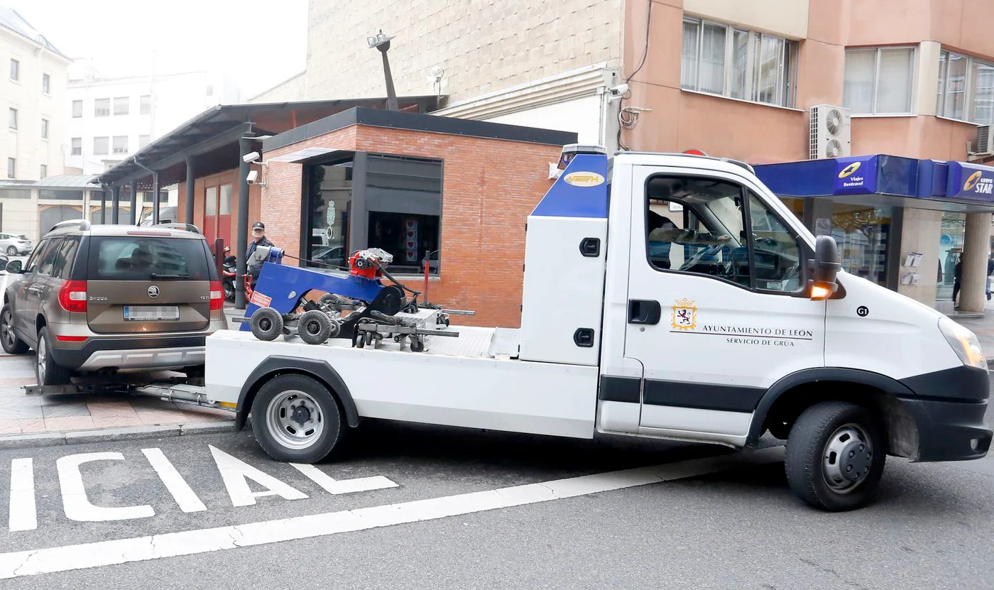 Una grúa municipal retira un vehículo de la Comisaría de Policía.