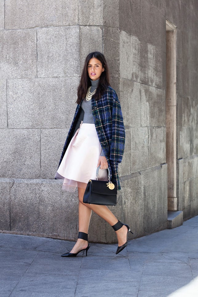 La falda a la rodilla con vuelo, en raso de seda rosa con tutú de tul blanco, es de Dior. Jersey de punto canalé, de Escada, y abrigo de lana, de Love Moschino. El bolso es el modelo Be Dior, de Dior; los zapatos de salón con elástico en el tobillo, de Jimmy Choo; y el collar de perlas, de Bimba y Lola.