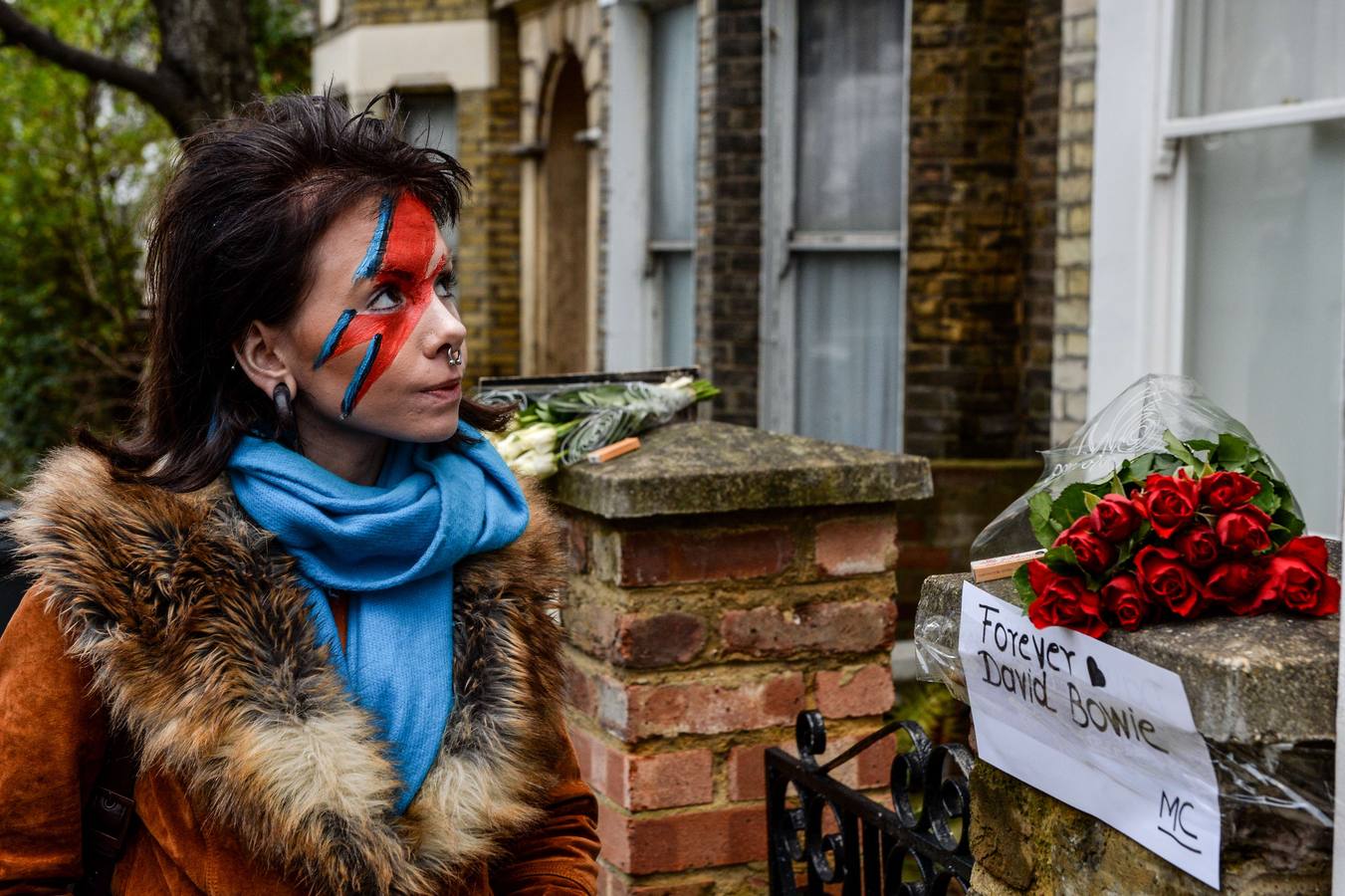 Una mujer con la cara pintada con el famoso rayo de Aladdin Sine, frente a la casa donde pasó su infancia David Bowie.