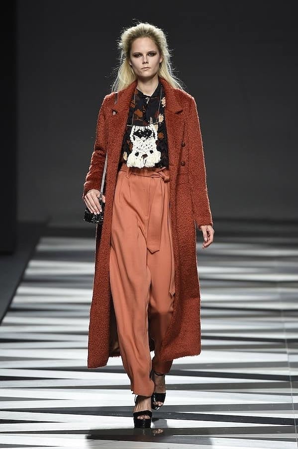 Abrigo largo combiando con pantalón 'baggy' en tonos naranja.