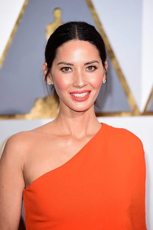 Olivia Munn lució un favorecedor moño bajo peinado con raya en medio y con un punto informal, al llevar algunos mechones sueltos. En su maquillaje destacan sus labios naranjas, combinados con su vestido.