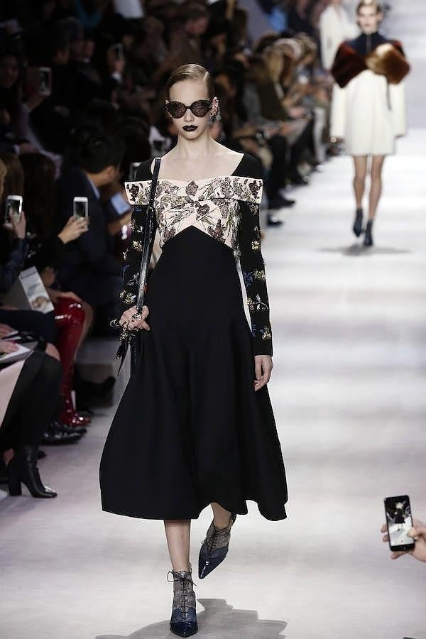 Vestido negro con vuelo en falda y mangas bordadas con flores.