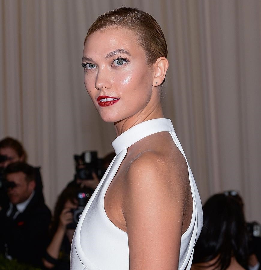 La modelo Karlie Kloss con un recogido con efecto mojado, labios rojos y extensiones de pestañas.
