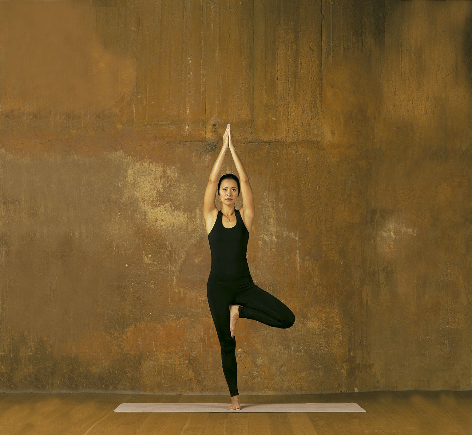 CON UNA PIERNA. Traslada el peso al pie derecho. Con la mano coloca el talón del pie izquierdo, cerca del pubis, con la planta apoyada en el muslo. Junta las palmas de las manos en el centro del pecho y, cuando sientas estabilizado el equilibrio, inspira y eleva los brazos manteniendo las palmas juntas. Mantén la postura cinco respiraciones y cambia de lado. PALABRA DE ESXPERTA. Fija la mirada en algún punto visible frente a ti durante todo el ejercicio. La clave del equilibrio está en la mirada.