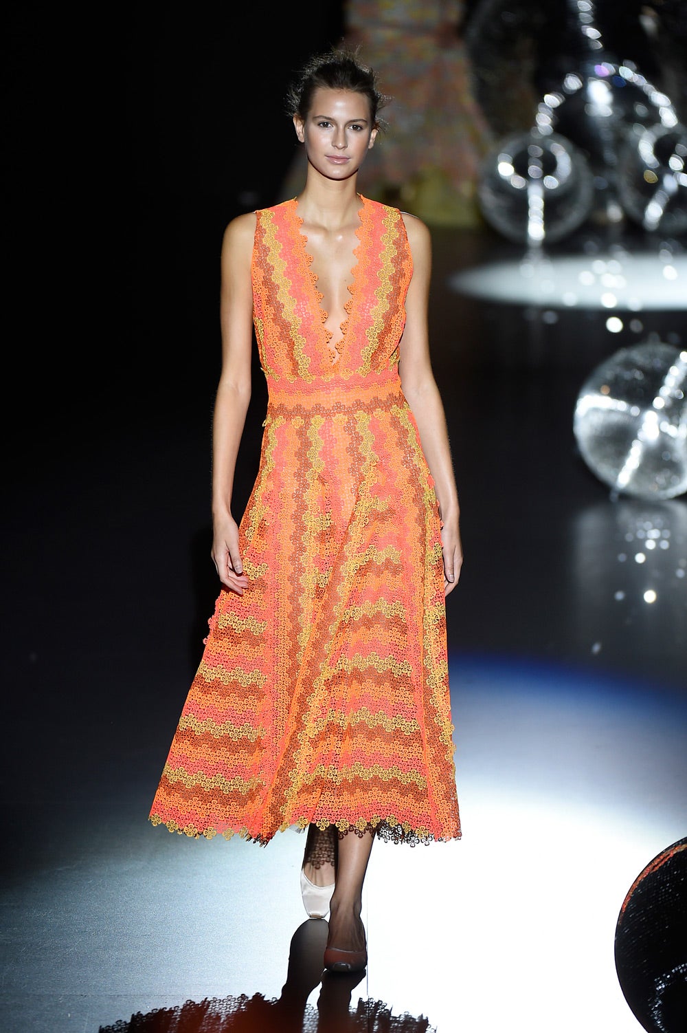 Vestido midi en tonos naranjas y rosas con escote pronunciado.