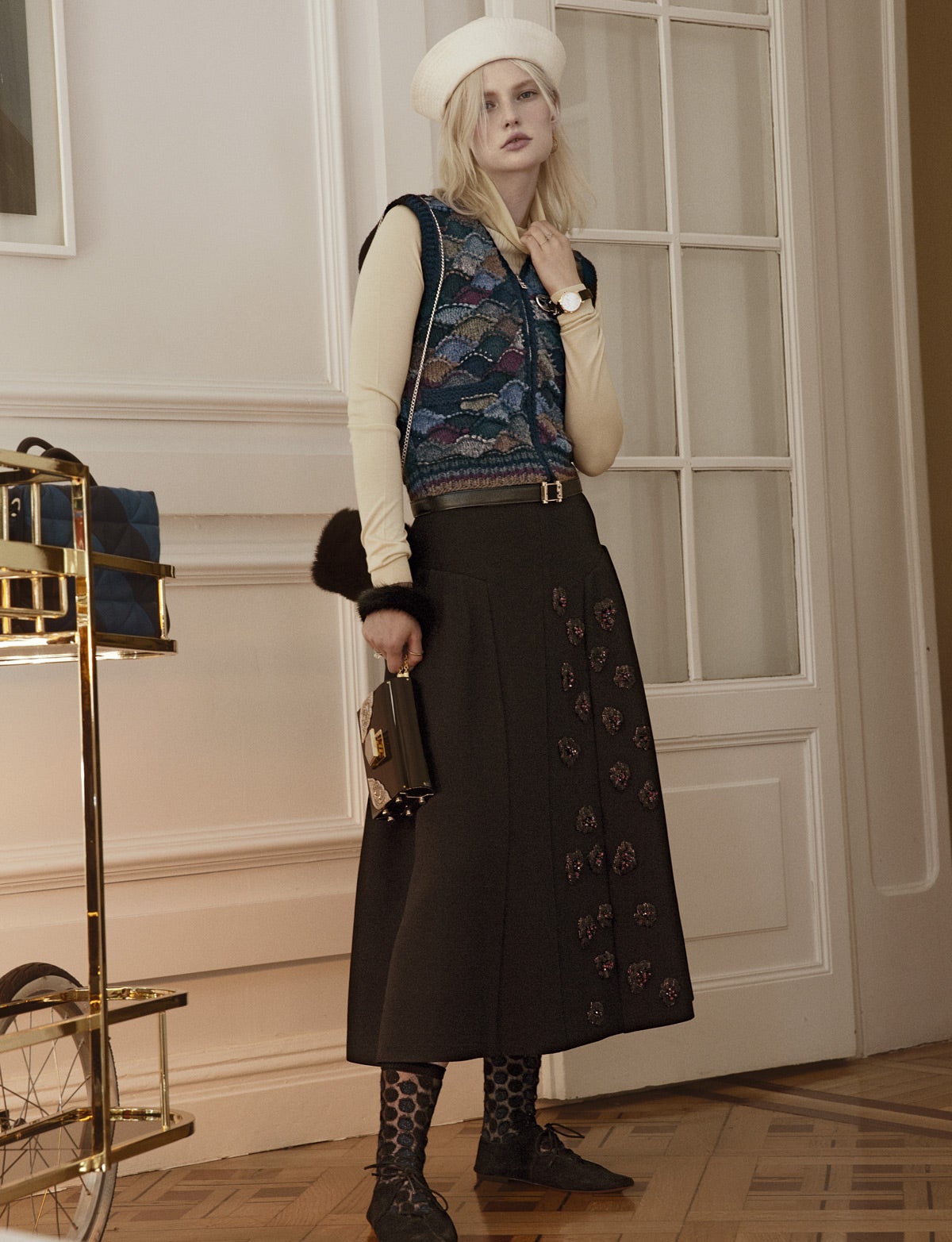 Chaleco de Prada y falda de Christian Dior, con jersey de cuello cisne y cinturón de Hermès. El sombrero marinero es de Prada; los zapatos, de Céline; y los calcetines, de Sonia Rykiel. Anillos de Sara Lasry y reloj de Baume & Mercier. Los bolsos que lleva la modelo los firma Pedro del Hierro, y el que hay sobre el mueble, Sonia Rykiel. Estilismo: Carolina Badía. Agradecimientos: Club Alma. Maquillaje y peluquería: Ricardo Calero (Talents) para Art Lab-Aveda y Chanel. Asistentes de fotografía: Germán Gómez y Nauzet Gaspar. Asistente de estilismo: Sandra Muñoz.