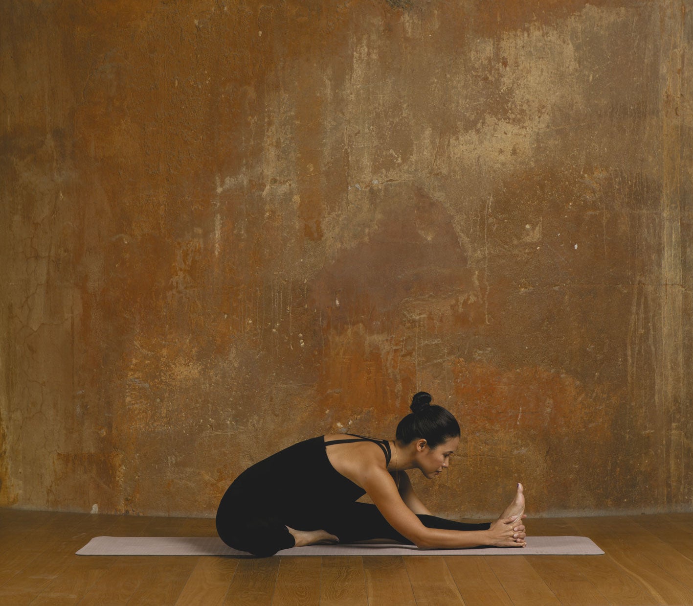 Siéntate en la esterilla con las piernas estiradas y la espalda recta. Dobla la pierna derecha y presiona la planta del pie contra el muslo izquierdo. Al inspirar, levanta los brazos por encima de la cabeza alargando el tronco. Al espirar, inclínate hacia delante y baja las manos para sujetar el pie o el tobillo de la pierna izquierda. Con cada espiración, intenta bajar un poco más. Respira cinco veces y repite con la otra pierna flexionada.  Palabra de experta.  No te obsesiones con que tu cabeza no toca la rodilla, porque es normal. Lo importante es no curvar la espalda.