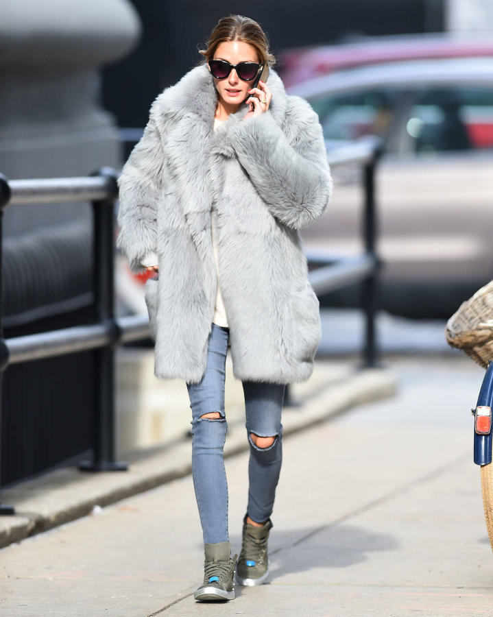 Olivia Palermo con abrigo de pelo gris, tejanos y deportivas.