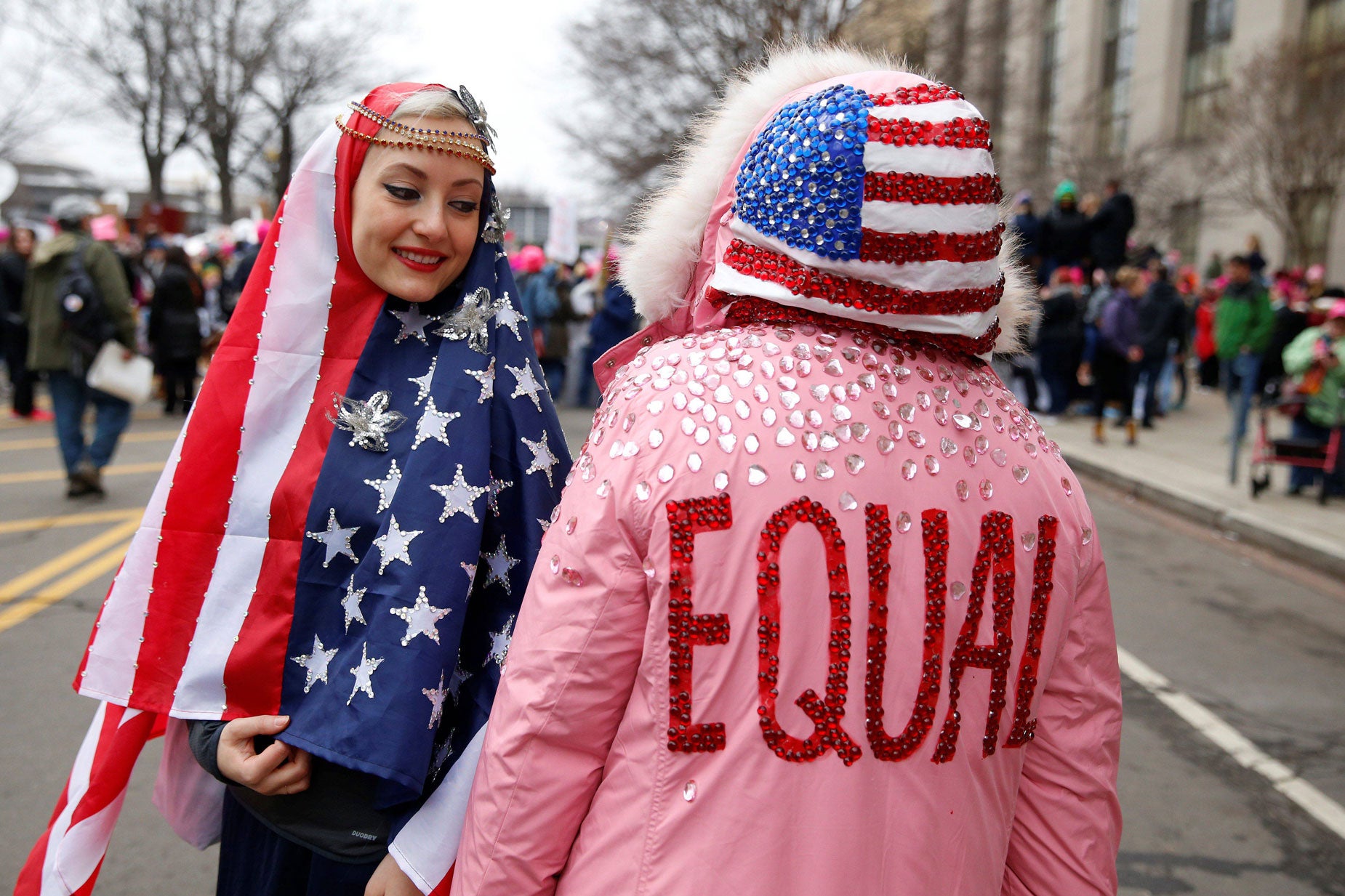 Dos mujeres con la bandera sobre sus cabezas: una en forma de capucha y otra cubriéndose la cabeza a modo de Hiyab.