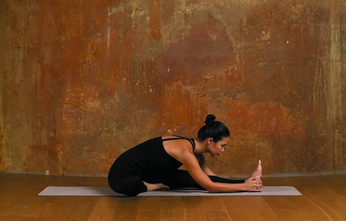 Empieza sentada en la esterilla, con la piernas estiradas y la espalda recta. Dobla la pierna derecha y presiona la planta del pie contra el muslo izquierdo. Cuando inspires, levanta los brazos por encima de la cabeza alargando el tronco. Al espirar, inclínate hacia delante y baja las manos para sujetar el pie o el tobillo de la pierna izquierda. Con cada espiración, aumenta la flexión, sin redondear la espalda. Palabra de experta. Con esta asana tonificarás tu espalda y calmarás tu mente.