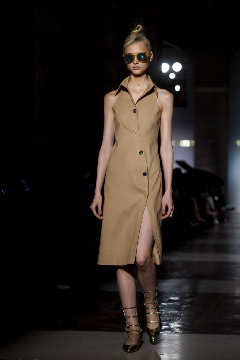 Vestido camisero en color cámel con botonadura de colores y ligera abertura en la falda. Las sandalias doradas, sin tacón, y de estilo romano.