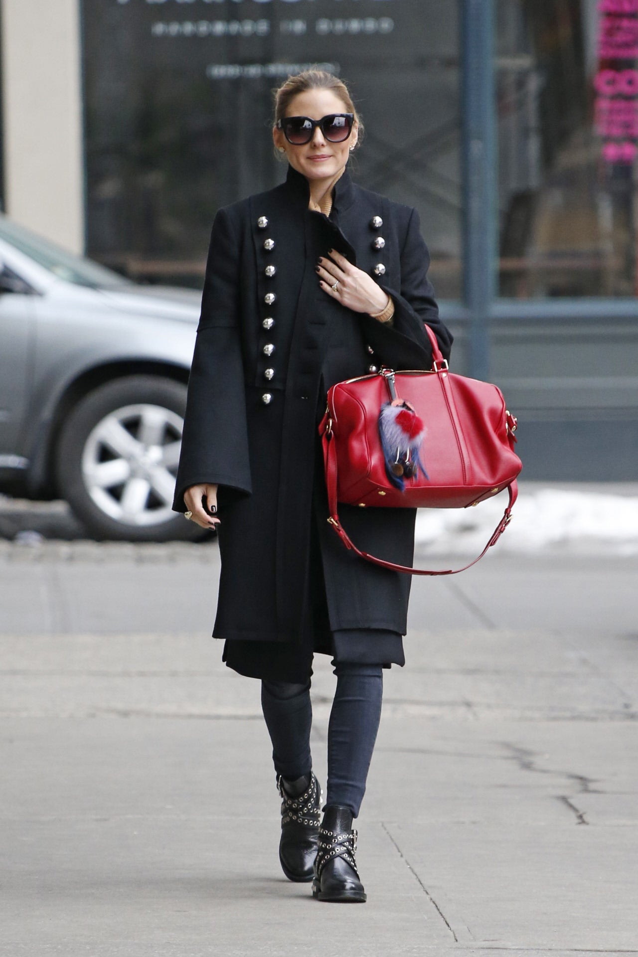 La bloguera luce un abrigo de Burberry de estilo millitar con botas con tachuelas y pantalón vaquero. La nota de color la pone el bolso rojo.