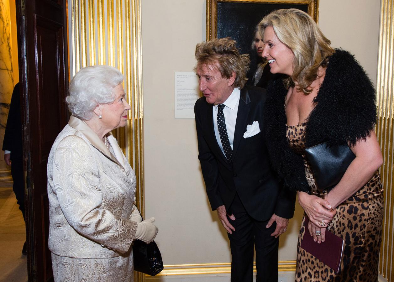 La reina Isabel II saluda a sir Rod Stewart y su mujer. El contraste de looks y estilos es de lo más llamativo.
