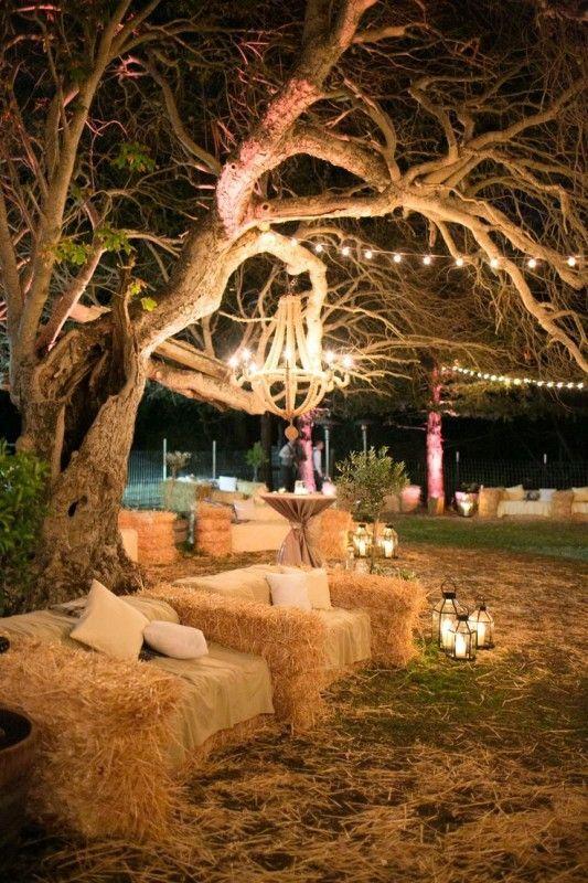 Para los espacios 'chill' de una boda en el campo apuesta por los sofás elaborados con fardos de paja y adornados con telas en tejido natural. Nos encanta la lámpara 'art decó' colgada del árbol como contraste (Foto: Pinterest).