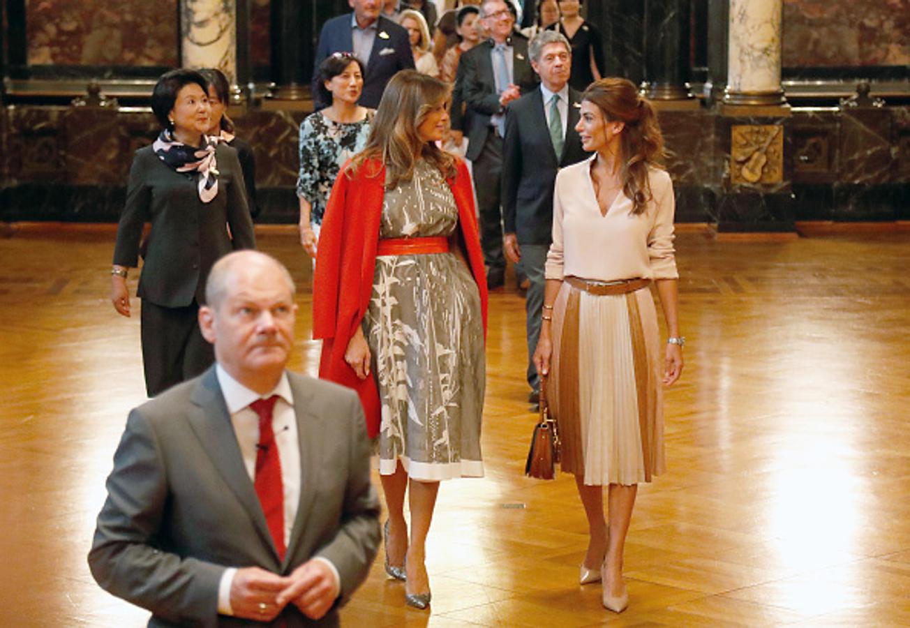 En el segundo y último día de la Cumbre del G20, la esposa del primer ministro argentino y la del estadounidense se reunieron con Olaf Scholz y ambas estuvieron muy acertadas con sus looks aunque sus estilos son muy diferentes. La argentina se enfundó una falda plisada en tonos maquillaje que combinó con una blusa y unos zapatos de salón en el mismo tono; la exmodelo apostó por un vestido con estampado de flores que le dio un toque de color al look con un abrigo y un cinturón en color rojo.