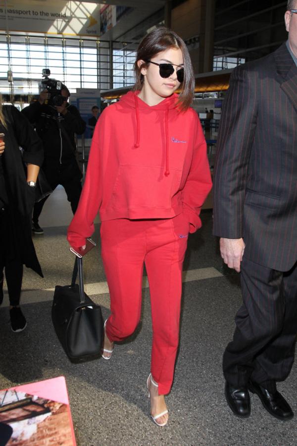 Para uno de sus viajes en avión, Selena Gomez sorprendió al combinar un chándal rojo con unas sandalias de tacón blanco.