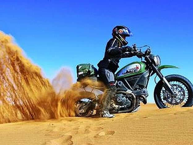 Alicia sacando su moto en una duna en Marruecos.