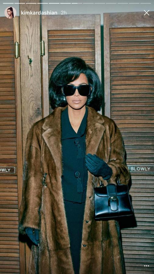 Kim Kardashian con u abrigo de pelo largo de color marrón. De accesorios lleva un bolso pequeño de color negro y unos guantes del mismo color, además de unas gafas de sol.