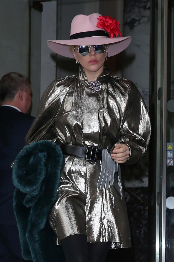 Lady Gaga saliendo del Hotel Langham de Londres. La cantante lleva una gabardina brillante en color plateado a modo de vestido y una pamela en color rosa claro.