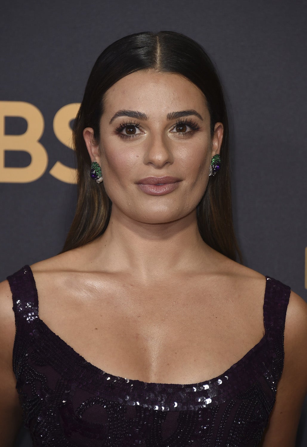 Lea Michele con melena suelta lisa y raya en el medio y acabado 'wet' en las raíces. En cuanto a su maquillaje, sombras doradas y pestañas XXL, y labios naturales.