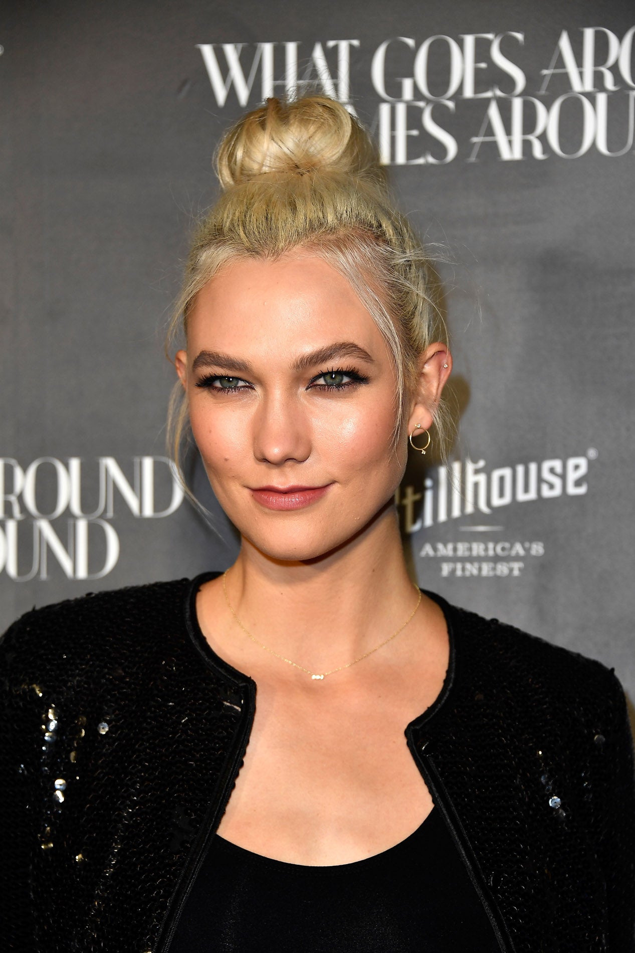 Es el peinado estrella de estas fiestas, el moño alto o 'top knot' te convertirá en la más guapa de tus eventos. karlie Kloss lo lleva con un mechones sueltos.