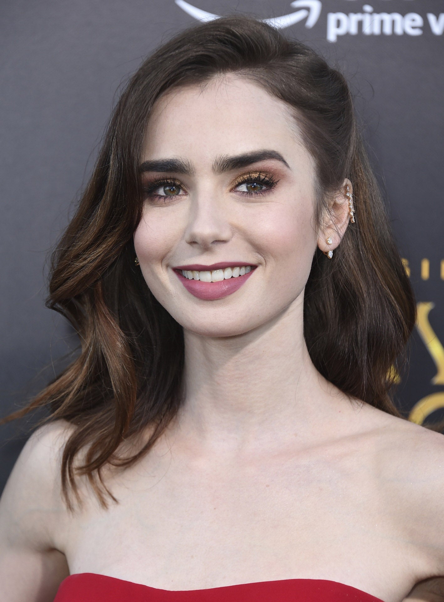 Un peinado sencillo pero perfecto es el que luce Lily Collins, con ondas ligeras, raya a un lado y semirrecogido. Ponle un pasador joya y tendrás el peinado 10.