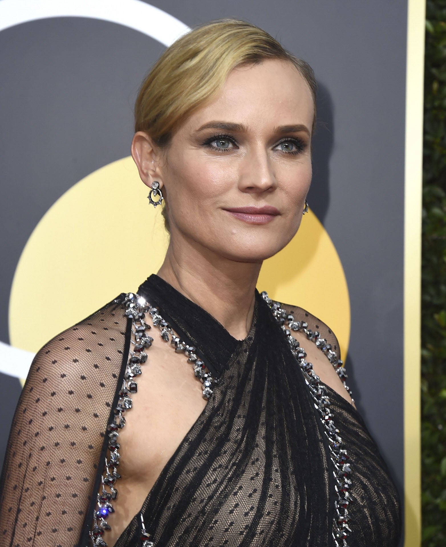 Diane Kruger con moño y raya lateral, sombras en tonos grises y labios rosas en la alfombra roja de los Globos de Oro 2018.