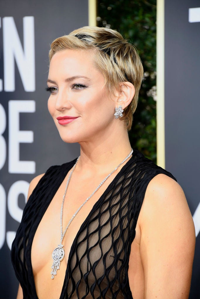 Kate Hudson, que ha recuperado su rubio platino, adornó su pixie con una cinta negra. Y completó su look con labios rojos y sombras beiges satinadas.
