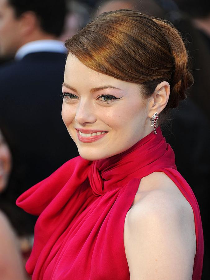 Emma Stone con un recogido clásico y flequillo lateral en los Oscar 2012 que combinó con eyeliner con rabillo y labios rosas.