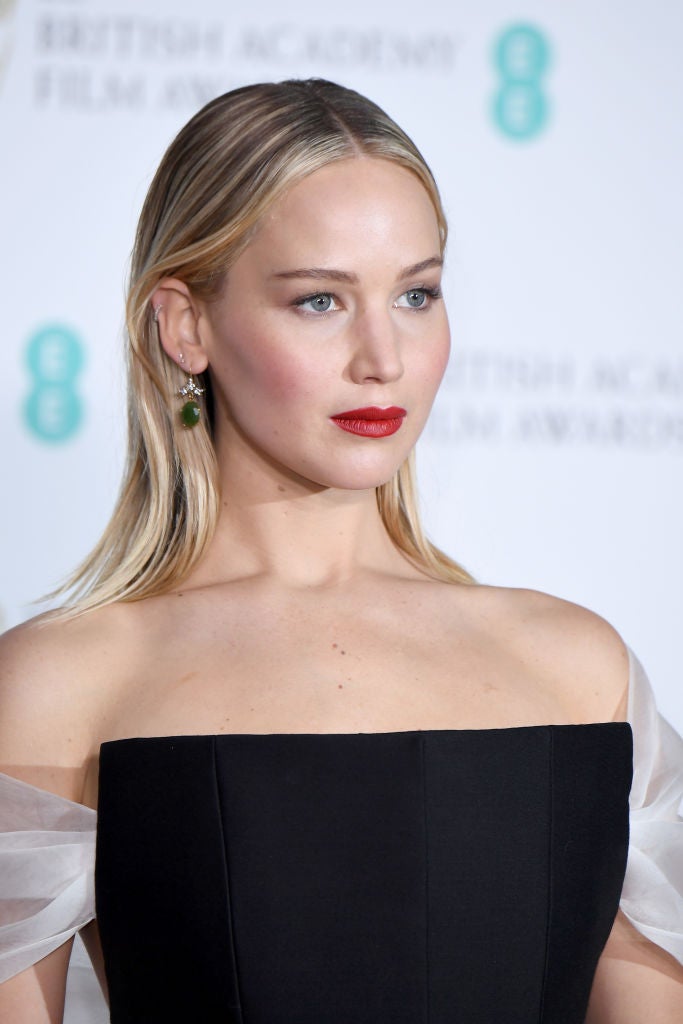 Jennifer Lawrence con melena suelta pulida y raya en el medio y un maquillaje que centró toda su atención en la boca, con labios rojos.
