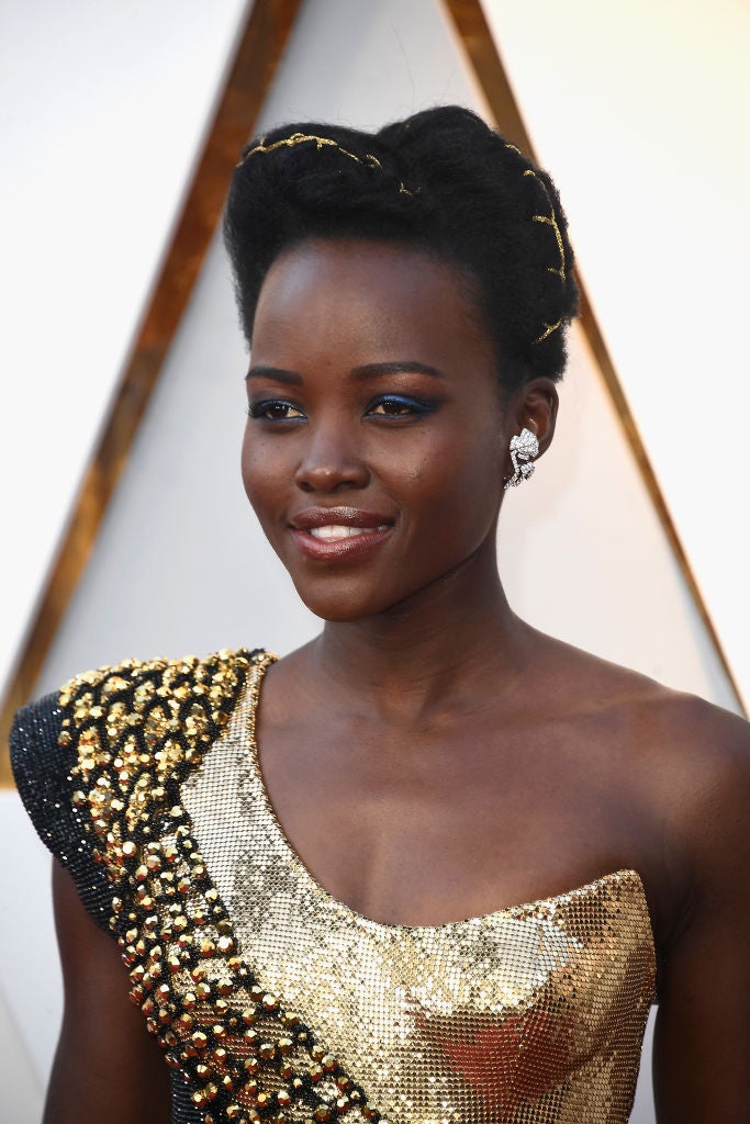Lupita Nyong'o con un recogido con trenzas que adornó con cinta dorada a juego con el vestido. En su maquillaje destacan las sombras azules.