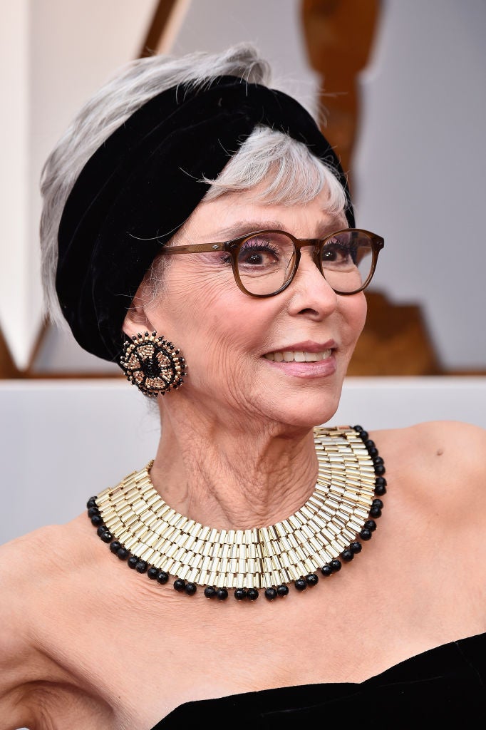 Rita Moreno adornó su pixie con un cinta negra de terciopelo. Y lució sombras lilas y pestañas XXL con labios nude.