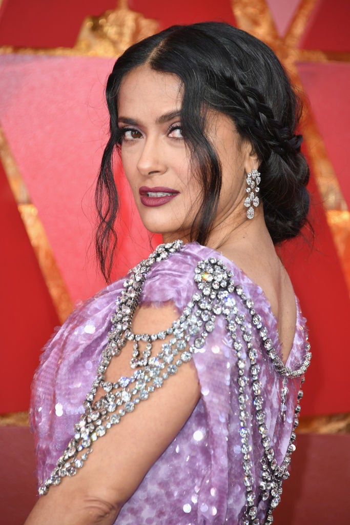Si quieres lucir un look romántico inspírate en el peinado de Salma Hayek: un recogido bajo, adornado con trenzas y mechones sueltos ondulados.