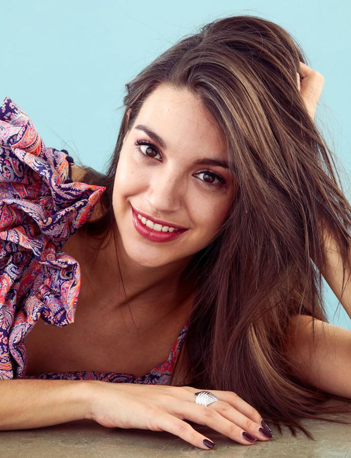 Para el maquillaje de Ana, se ha elegido un solo color y a partir de ahí se ha construido un look que incluye ojos, labios y uñas. La mirada, en rojo oscuro, con unos ojos definidos con eyeliner para crear un efecto de profundidad. Vestido de Loewe y anillo de Aristocrazy.