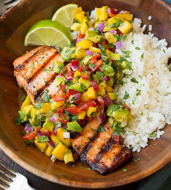 Salmón a la parrilla acompañado de una ensalada de aguacate, mango, tomate, cebolla y arroz.