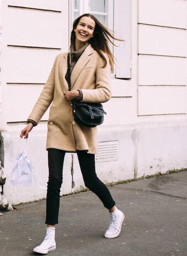 Una combinación básica y que siempre funciona: pantalón pitillo negro, abrigo cámel de entretiempo y zapatillas Converse.