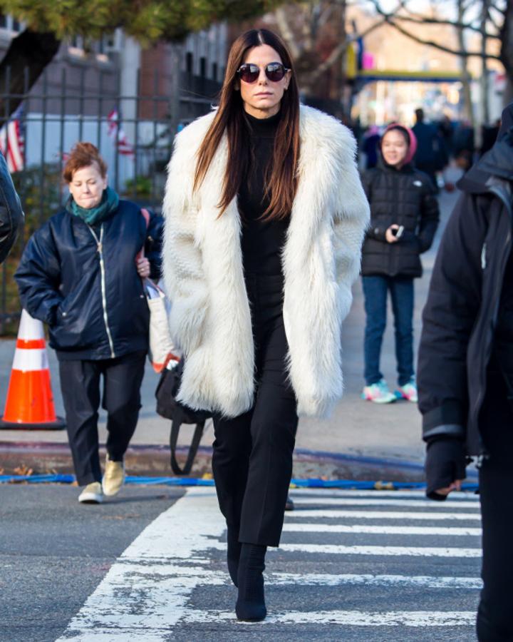 Sandra Bullock es otro icono de elegancia aún a pesar de haber pasado los 50. Este look 'total black' contrastado con este abrigo de pelo en color blanco, que lució por las calles de New York, es muestra de ello.