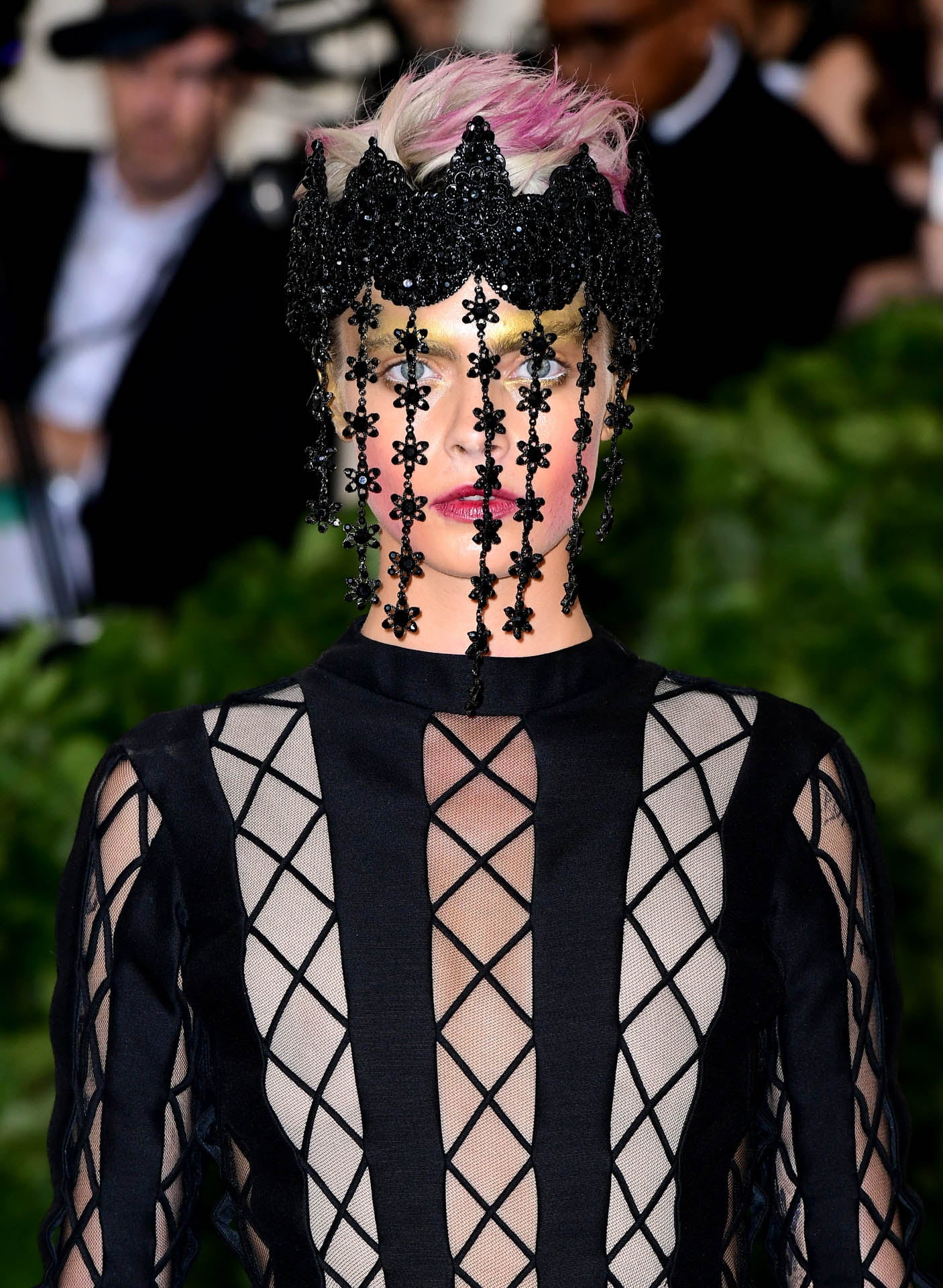 Otra de las famosas que más arriesga siempre es Cara Delevingne. Y en esta ocasión, de nuevo nos ha dejado sin palabras. La actriz ha elegido un tocado negro de pedrería en modo de corona, que cubría su cara y debajo del cual vemos un maquillaje espectacular en tonos dorados y rosas. En el pelo también nos han sorprendido sus mechas rosas.