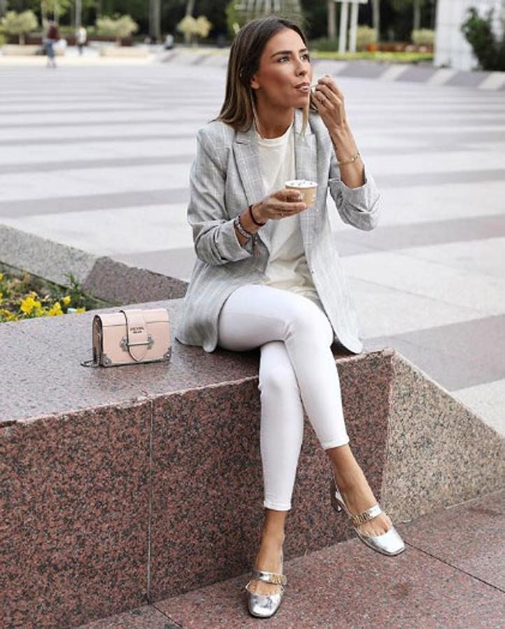 Marta Carriedo, perfecta para un día de trabajo, combina esta americana de cuadros grises de H&M con unos pantalones blancos y camiseta básica blanca. 'Outfit' que ha completado con unos zapatos de tacón plateados de Dior y bolso de Prada.