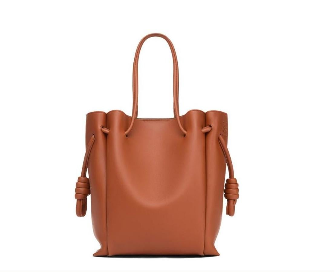 Con Loewe no fallas nunca. Este bolso está confeccionado con piel de ternera graneada y lleva los característicos nudos del bolso Flamenco. Sus asas y ribetes tiene forma de cilindro. Este accesorio cuenta con el tamaño perfecto para llevar y organizar los esenciales del día a día.